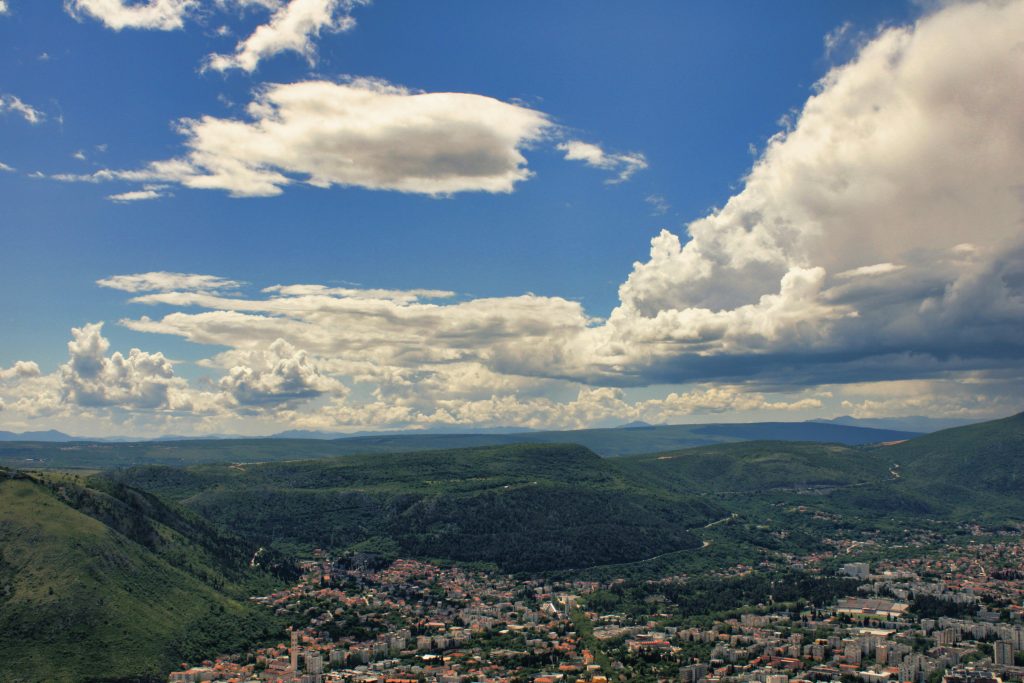 A stunning aerial view of Mostar with lush mountains and vibrant clouds.